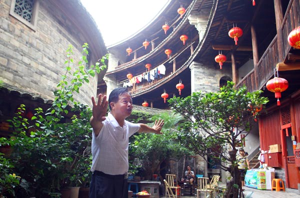 Lin Rigeng, a tulou owner in Yongding county, Fujian province, introduces visitors to the ancient dwelling complex. PHOTO BY ZOU HONG / CHINA DAILY 