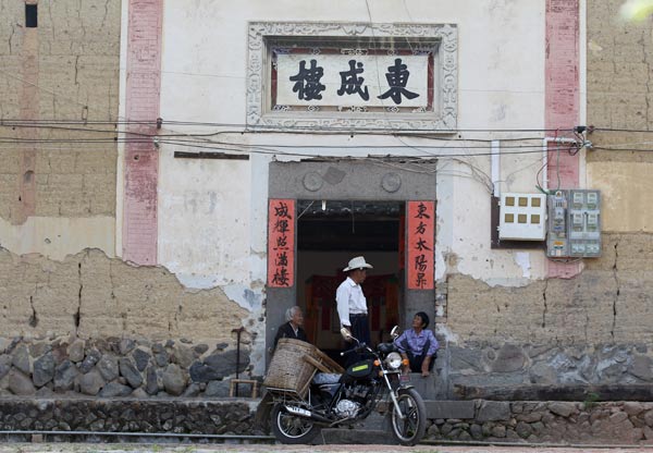 Residents of Dongcheng Lou sit at the entrance of the building. 