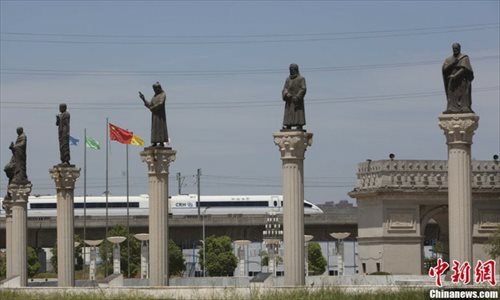 A high-speed train passes behind a row of faux-Corinthian columns that line a viaduct and are topped with Greek gods near the university gates. Photo: chinanews.com