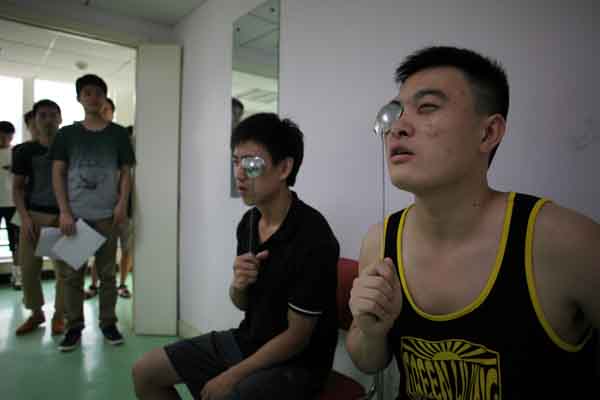 College students intending to join the army take eyesight tests at a Beijing hospital on Saturday. A Beijing Sport University professor says students' physical condition has been declining since 1995.WANG JING / CHINA DAILY