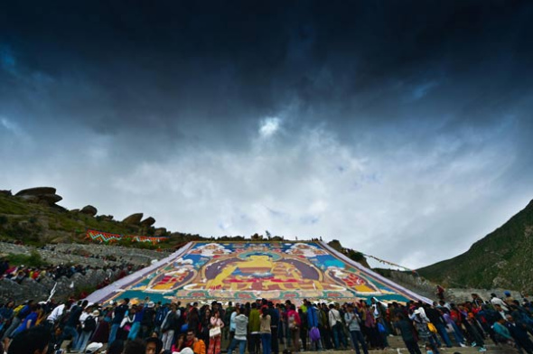 Visitors look at a giant thangka on the mountain behind Drepung Monastery in Lhasa, capital of the Tibet autonomous region, Aug 6, 2013. [Photo/Xinhua]