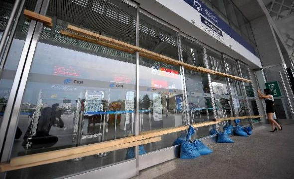 Glass doors are framed with wood at the Haikou East Station in Haikou, capital of south China's Hainan Province, Aug. 13, 2013. Local meteorological department Tuesday raised the alert on strong typhoon Utor to the highest level. Utor has escalated to become a strong typhoon Tuesday morning, and is expected to make landfall in Hainan and south China's Guangdong Province Wednesday. (Xinhua/Guo Cheng)