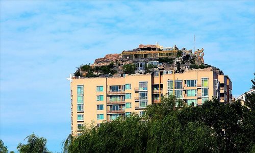 A privately built villa is spotted at the top of a residential building in Beijing on August 12, 2013. The villa, hidden among the rockeries and bushes, has prompted complaints from neighbors downstairs. Photo: Xinhua