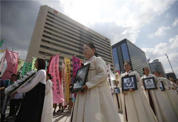 Participants carry portraits of Korean women who were forced into sexual slavery by the Japanese military during World War II during a requiem ceremony for former comfort woman Lee Yong-nyeo in central Seoul on Wednesday. Kim Hong-Ji / Reuters