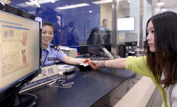 A woman scans her fingerprint at a police station in Shanghai, on May 30, 2013. The information will be recorded into her ID card. Shanghai residents will be required to have their fingerprints scanned when obtaining a new ID card starting from July 1. The move is aimed to curb counterfeiting and the false use of ID cards. Shanghai has piloted the work since Jan 1, 2013. Up to now, more than 200 police stations have already issued 10,756 new ID cards with fingerprint information. [Photo/Xinhua]