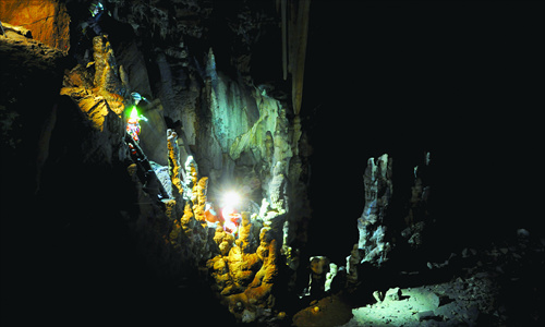 Light from one cave explorer's torch reveals the colorful stalagmites within Tangren Cave in Fangshan district. Photo: Courtesy of Beijing Caving Association 