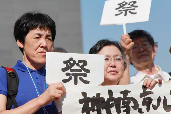 A group of Japanese peace activists pay their respects to victims of the Nanjing Massacre in the capital of Jiangsu province on Thursday, the 68th anniversary of Japan's surrender in World War II. At least 300,000 Chinese people were killed by Japanese soldiers when they took Nanjing, then China's capital, in December 1937, in a six-week rampage of looting, rape, torture and murder. The signs read: In memory of the dead. [LIU JIANHUA / FOR CHINA DAILY]
