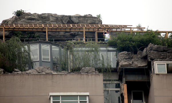 Workers begin the demolition of the rock-covered rooftop villa in Beijing's Haidian district on Thursday, three days after the district's urban patrol officers deemed the structure illegal and ordered it removed. [Photo by Wang Jing / China Daily]