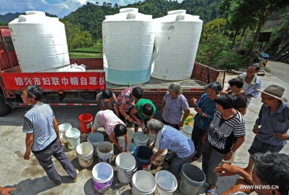 A truck brings drinking water to villagers in Xinchang County, east China's Zhengjiang Province, Aug. 15, 2013. Xinchang has suffered a lingering heat wave since July, leaving water sources dried up and 22,300 people short of drinking water. (Xinhua/Tan Jin)