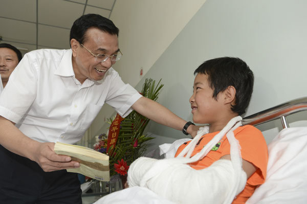 Premier Li Keqiang visits 12-year-old earthquake victim Cao Jiandong in Minxian county, Northwest China's Gansu province, on Saturday. The county was hit by an earthquake on July 22. [Photo by Liao Pan/China News Service] 