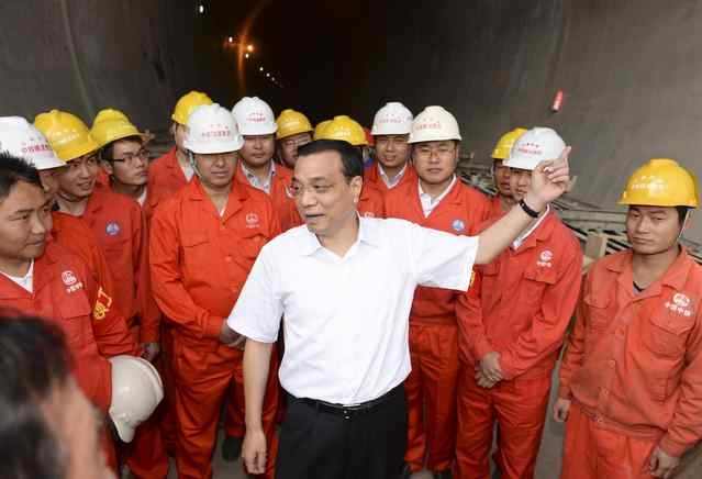 Premier Li Keqiang, center, talks to workers during a visit to the construction site of the Muzhailing tunnel construction site on the Lanzhou-Chongqing Railway in Dingxi, Gansu province, on Aug 18, 2013. [Photo provided to chinadaily.com.cn]