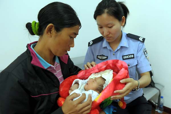 A woman holds a baby who police say she bought in Sichuan province, after they were stopped by police in Xuzhou, Jiangsu province, in early June. Experts in baby trafficking said parents who sell their babies should not get their children back. [Hou Qiguang / for China Daily]