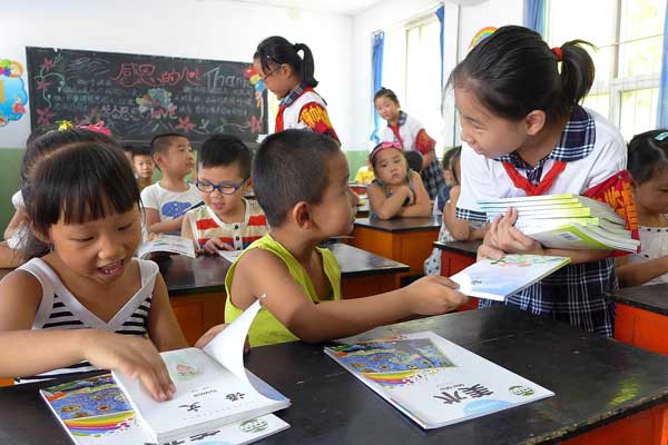 First-grade students receive new textbooks at a primary school in Handan, Hebei province, on Wednesday. Parents and educators are discussing ways of reducing the academic burden on young Chinese students. Hao Qunying for China Daily