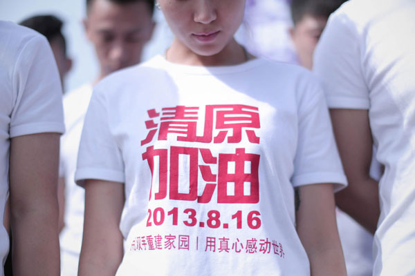 A volunteer mourns for flood victims, whose T-shirt printed with words come on ! Qingyuan, during a memorial service in Qingyuan county, Fushun, Northeast China's Liaoning province, Aug 24, 2013. [Photo/Xinhua]