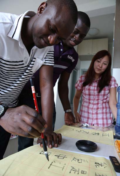 Kibirango Edwin (left), a student from Uganda, practices Chinese calligraphy with classmates in his dormitory at Jiangsu University in Zhenjiang. Yang Yu / for China Daily