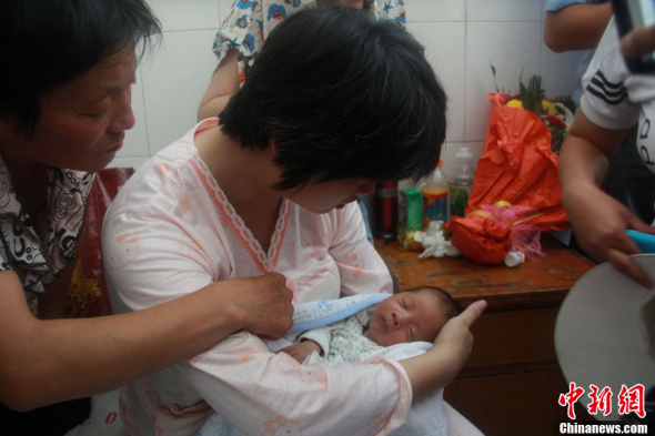 Wife of Lai Guofeng holds her baby in arms on August 5, 2013. The newborn baby who was allegedly sold to human traffickers by an obstetrician in northwest China's Shaanxi province was returned to his parents on Monday, and DNA tests confirmed the baby is Lai's son, local police said. (CNS Photo/Zhang Yichen) 