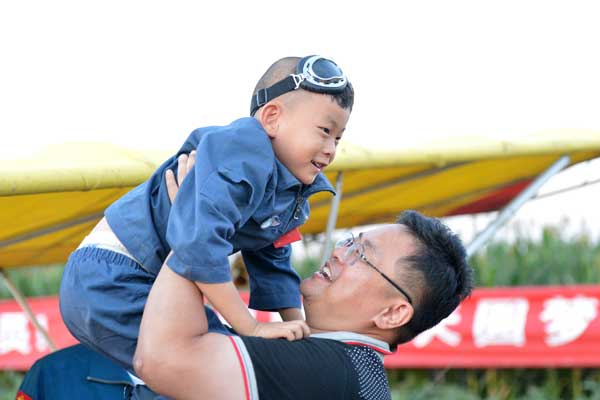He Liesheng celebrates with his son, 5-year-old He Yide, after the boy successfully piloted a fixed-wing plane around Beijing Wildlife Zoo on Saturday. The Eagle Dad seeks to have his son recognized as the youngest pilot in the world. [Provided to China Daily]