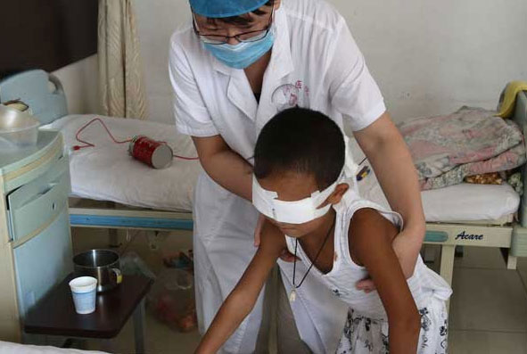 Guo Bin, aided by a doctor at Shanxi Eye Hospital in Taiyuan, tries to walk during a rehabilitation training program that started on Sunday. [ZHANG YUN / CNS]