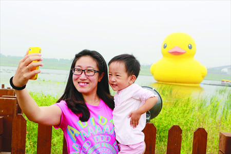A mother and son pose with Rubber Duck on Sunday, after its nose job.Photo: Li Hao/GT