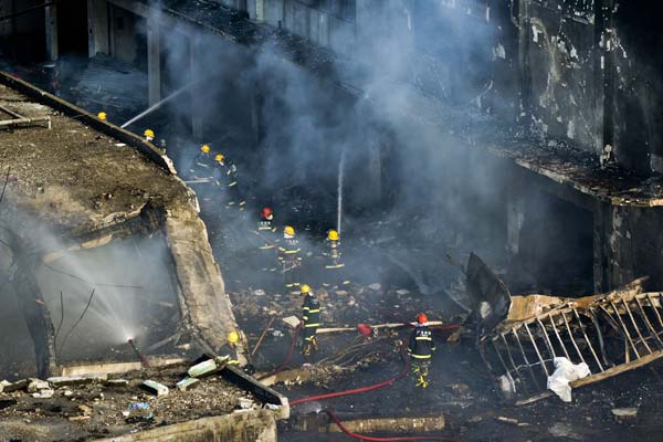 Firefighters put out a blaze after an explosion ripped through a roadside warehouse for shoe-making materials in Guangzhou on Tuesday, killing at least four and injuring 36. Thirteen children from a nearby kindergarten were among the injured. Zhou Wei / for China Daily