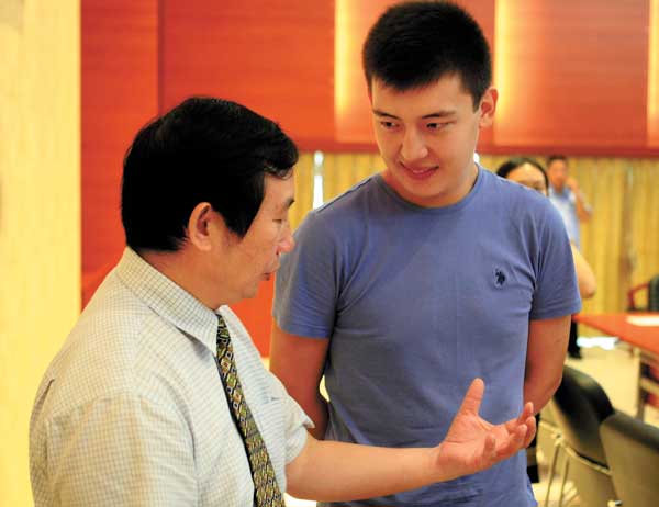 Li Jianbao, president of Hainan University, praises Tulenov Ruslan for donating blood after the opening ceremony of the university's new semester on Wednesday. Huang Yiming / China Daily