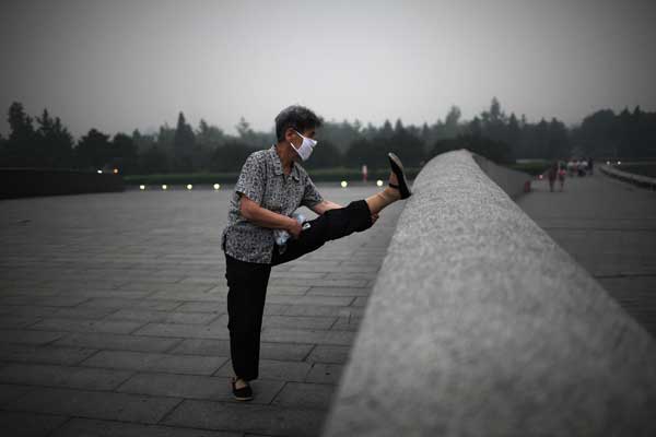 A Beijing resident defies the heavily polluted air to take her morning exercise. [Photo/Xinhua]