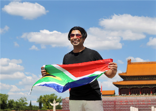 Mikail Hansa from South Africa has a photo taken with his country's national flag at Tian'anmen Square on Aug 30, a day when the PM2.5 readings in some parts of Beijing were extremely low, at only 4 micrograms per cubic meter. Zhou Hong/China Daily