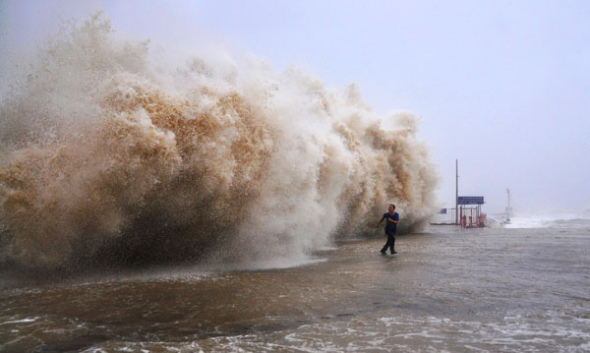 A man runs away from big waves at a dock in Shantou, Guangdong province on Sept 22, 2013. [Photo/Xinhua]