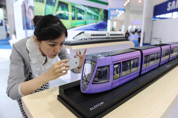 A woman takes photos of a tram model at a trade fair in Shanghai in May. Shanghai is proposing a tram system of six lines over 90 kilometers of track in Songjiang district and asking for public input until Oct 6. Lai Xinlin / for China Daily