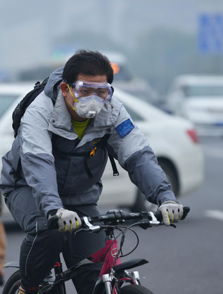 A man wears a face mask while riding a bicycle in Beijing on Sunday to protect himself from severe air pollution. [Photo/Xinhua] 