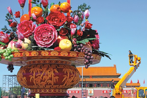  A worker examines a giant basket of artificial flowers and fruits in the center of Tian'anmen Square. The display was built to send blessings to the motherland. [Photo by Wang Jing/China Daily]