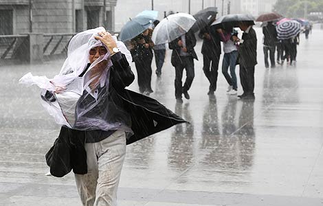 A woman uses a sheet of plastic to protect herself from rain brought by Typhoon Fitow in Shanghai, Oct 7, 2013. [Photo/Xinhua]