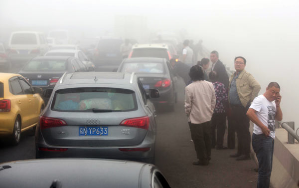 People are left waiting on an expressway in Weifang, Shandong province, after a series of collisions blocked the road on Monday amid heavy haze. Smog shrouded North China in the last few days of the weeklong National Day holiday. Mao Yanzheng / China Daily