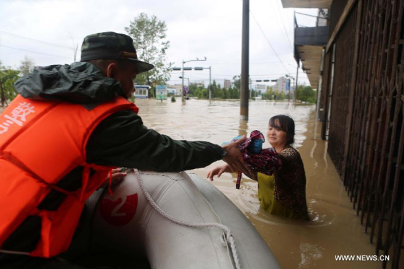 A soldier rescues a woman trapped in the flood caused by Typhoon Fitow in Taoshan Town of Wenzhou City, east China's Zhejiang Province, Oct. 7, 2013. Typhoon Fitow brought torrential rainfalls to Zhejiang on Monday. (Xinhua/Guo Guangjie) 