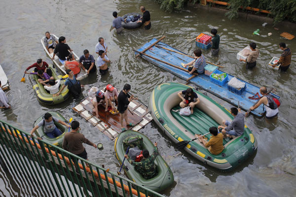 Residents in an area of Yuyao that was still underwater on Thursday use boats and makeshift rafts as part of the rescue effort. Gao Erqiang / China Daily