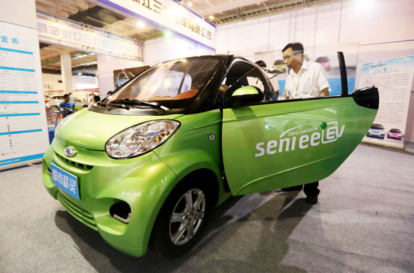 A man checks out an electric mobile at a new energy auto show in Beijing in July. The capital plans to tackle air pollution by promoting the use of green vehicles and cutting annual gasoline and diesel fuel consumption.[Photo/Xinhua]
