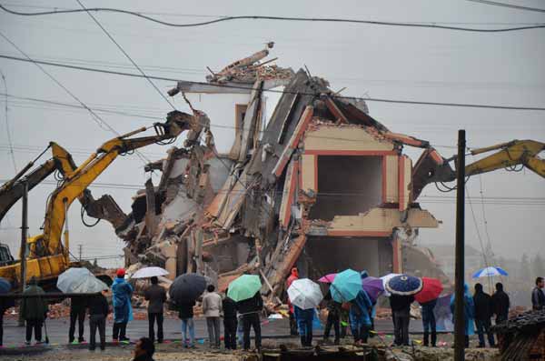 People watch a house being demolished in Wenling cityk, Zhejiang province, after its owner reached an agreement with the local government. [For China Daily] 