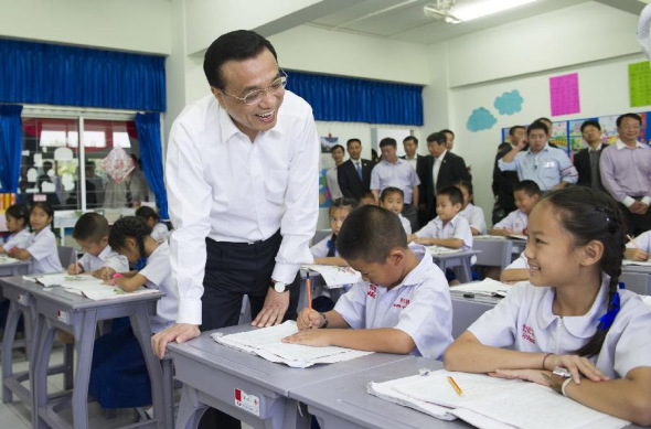 Chinese Premier Li Keqiang talks with third-grade pupils who are learning Chinese characters at a Chinese language-teaching school in Chiang Mai, Thailand, Oct. 13, 2013. Li paid a visit to the 110-year-old Chinese language-teaching school in Chiang Mai on Sunday. (Xinhua/Huang Jingwen)