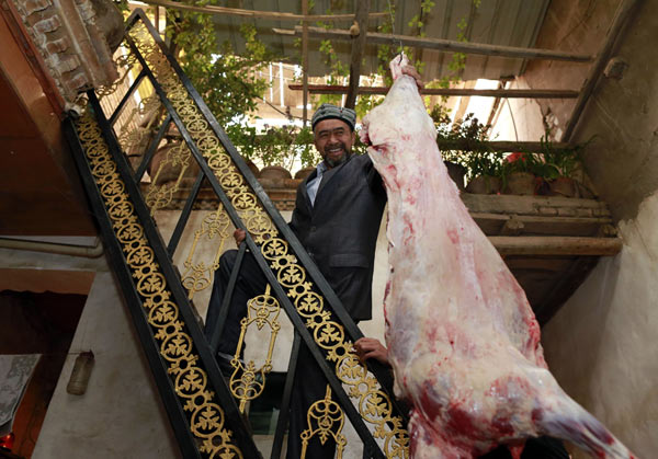 Hat shop owner Parhat Turson, 54, shows off a slaughtered sheep at his Kashgar home on Tuesday. Slaughtering sheep is a Muslim tradition for Eid-al-Adha. It is the second year we bought a sheep for Corban Festival. We couldn't afford them before, he said.Photos by Feng Yongbin / China Daily 