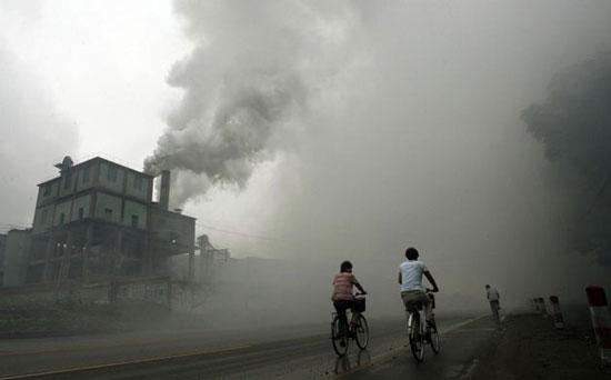 Yutian, Hebei province: Cyclists ride through a cloud of pollution produced by a nearby factory.