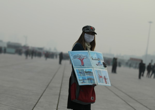 A woman shows blue sky photos of Beiing at a time when the capital was shrouded with serious smog again on Friday. The WHO's cancer agency classified air pollution as cancer causing. [Wang Jing/China Daily]