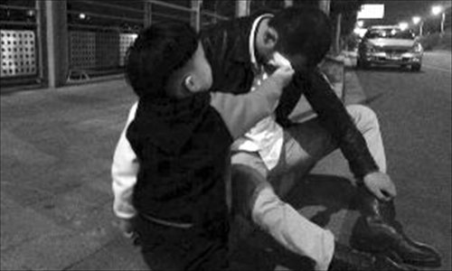 A two-year-old wipes the face of his drooling-drunk father after he had passed out on a curb in Nanjing, Jiangsu Province late on October 18. Photo: Modern Express
