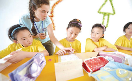 A foreign teacher assists her students during an English class at a summer camp in Yangzhou, Jiangsu province. Meng Delong / for China Daily