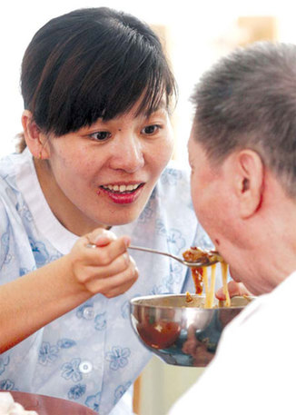 A staff member with a care center in Tianjin looks after an elderly man in June. Many people working in the public welfare industry could easily be suffering from depression. Liu Dongyue / Xinhua