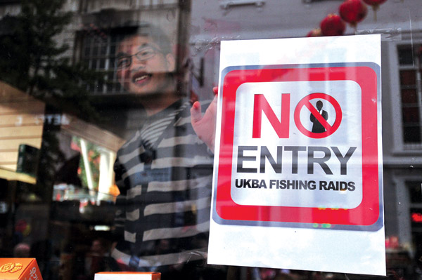 A poster is placed in a shop window during a protest against raids by the United Kingdom Borders Agency in Chinatown in central London on Tuesday. CARL COURT / Agence France-Presse