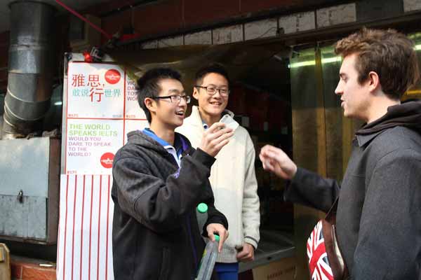 Two high school students buy goods from the foreign owner of a grocery store near No 2 High School Affiliated to Beijing Normal University on Monday. [Photo provided to China Daily]