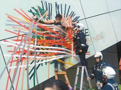 Caught on tape: A man surnamed Xie talks with a Taipei policeman after he taped himself on a wall to impress his girlfriend on October 27. Photo: United Daily News