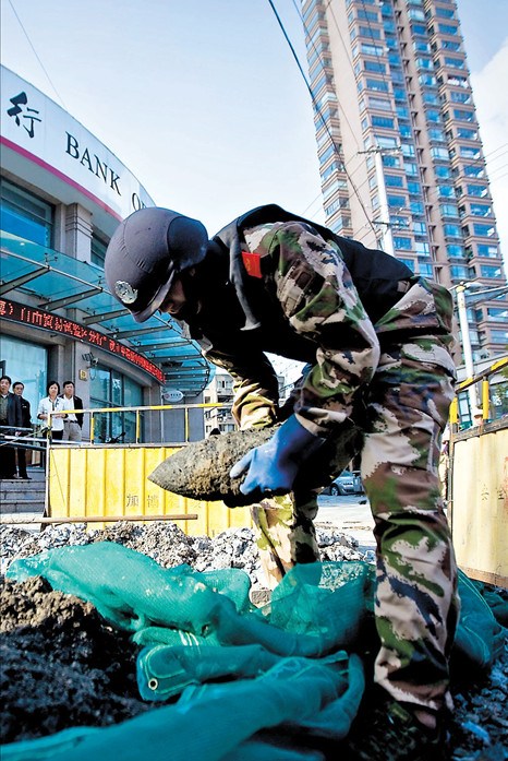 A firefighter removes a shell uncovered during digging in Zhabei District Monday. Four were found at the site.(Kou Cong) 