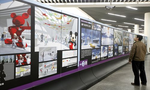 A passerby at People's Square Station Wednesday examines six proposed designs for the interior of the planned metro station at Shanghai Disneyland.