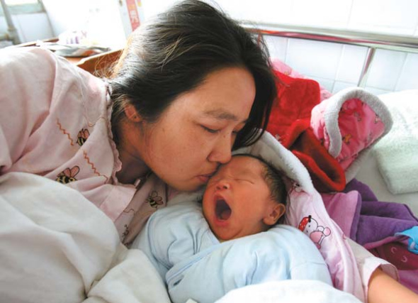 Liu Xianhong kisses her son on Thursday after they were reunited at a hospital in Tongcheng, Hubei province. The boy was stolen from the hospital on Sunday, 30 hours after being born. Police have arrested a suspect, who they say decided to steal a baby because she is infertile. Photo provided to China Daily